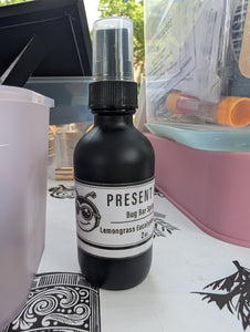 Black bottle of 'Present' bug bar spray on a table with a blurred background
