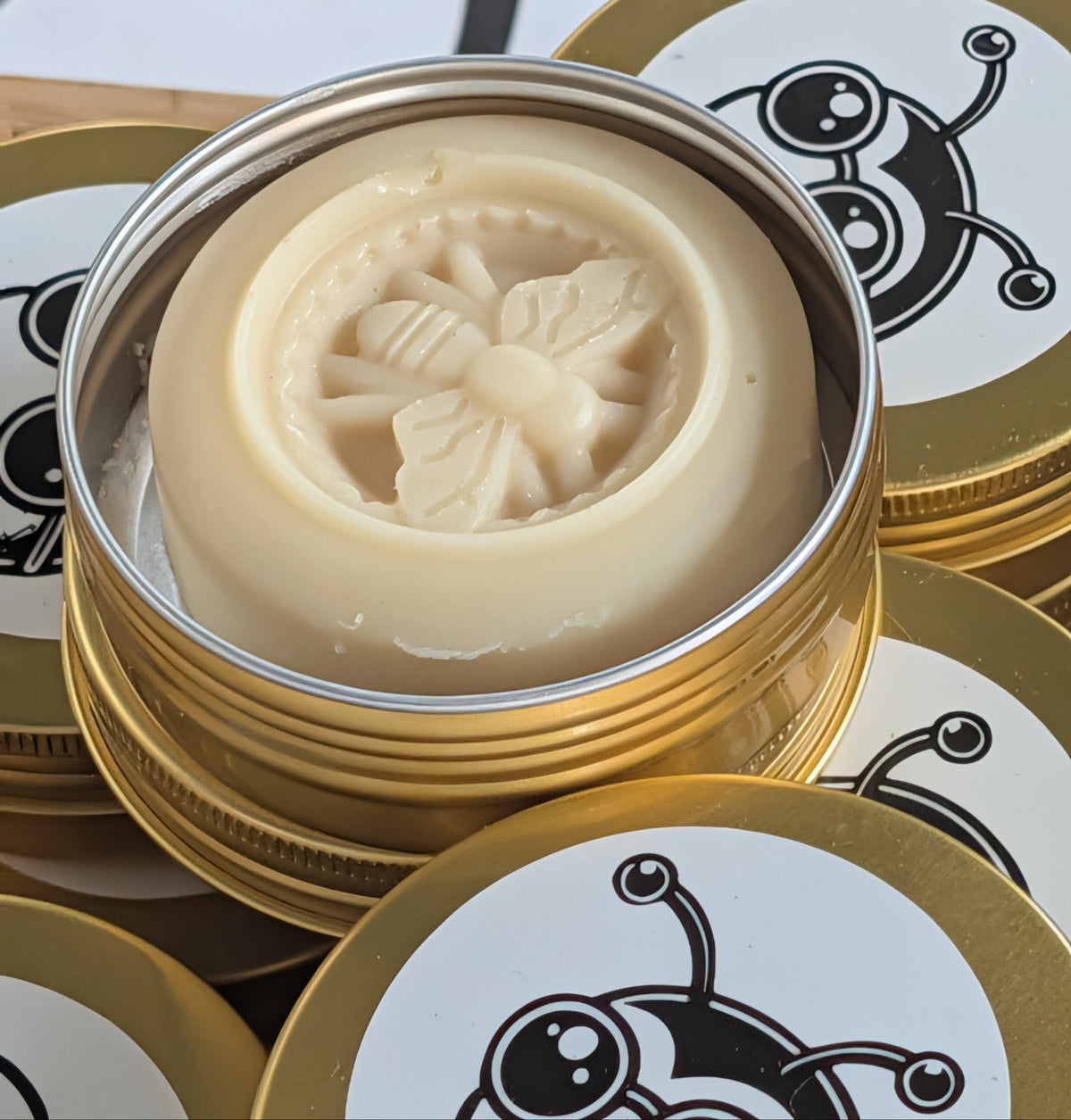 Bar of soap with bee design in a gold tin on a decorative surface