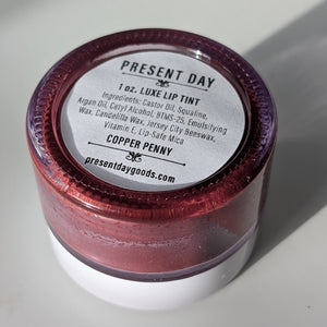 Jar of Present Day luxe lip tint with a white label on a light background