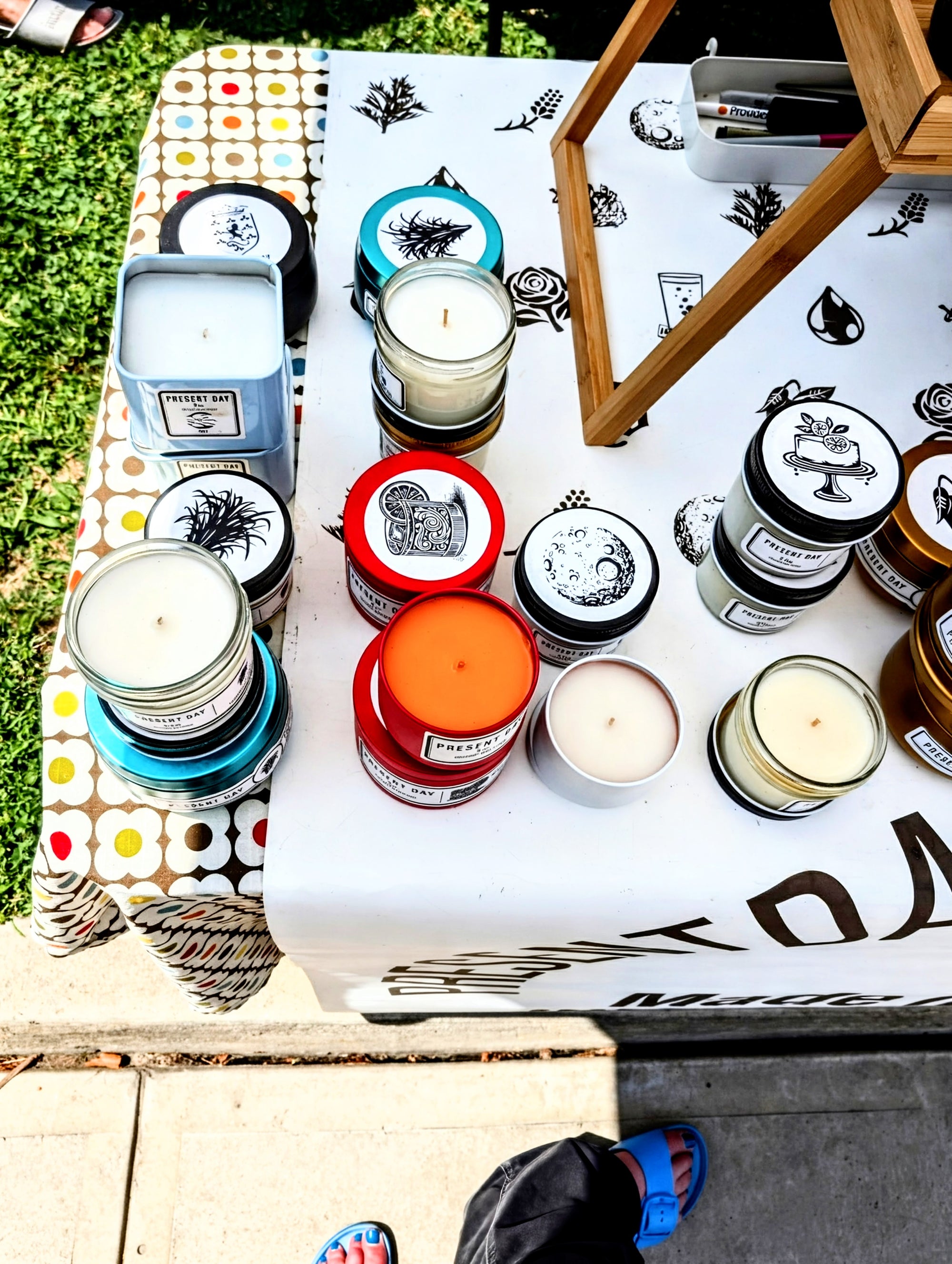 Assorted candles with visible branding on a table outdoors.