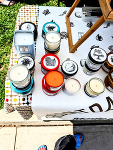 Assorted candles with visible branding on a table outdoors.