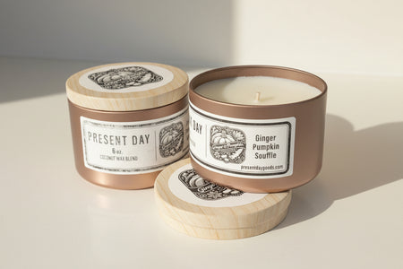 Two candles from Present Day with labels on a light surface.