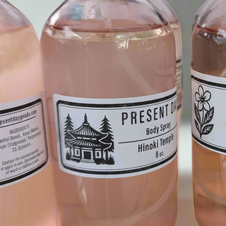 Bottle of Present Day Body Spray with a black cap on a white background