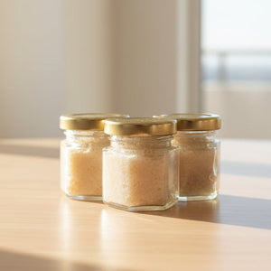 Jars of lip sugar scrubs with gold lids on a wooden surface