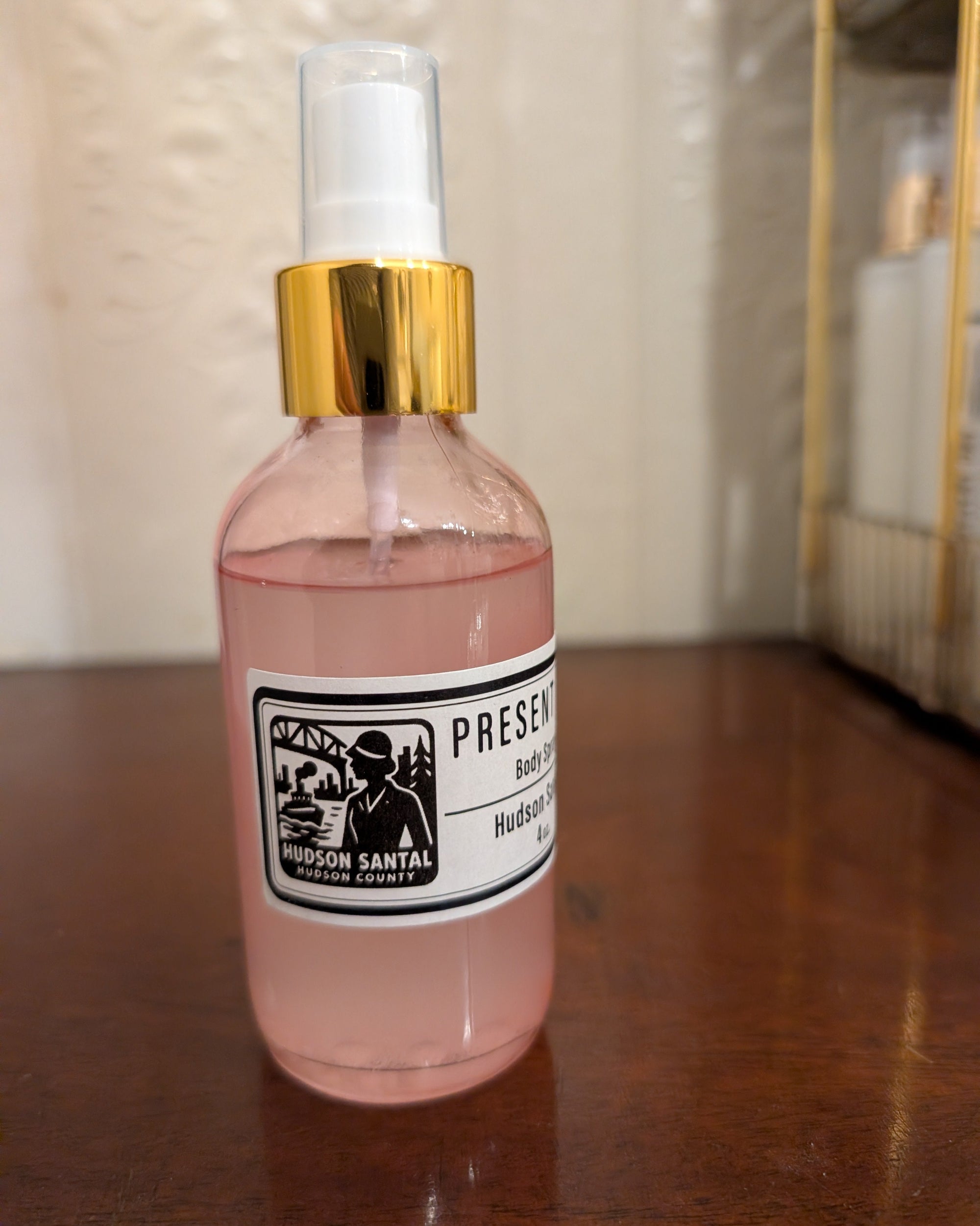 Pink spray bottle with gold cap on a wooden surface