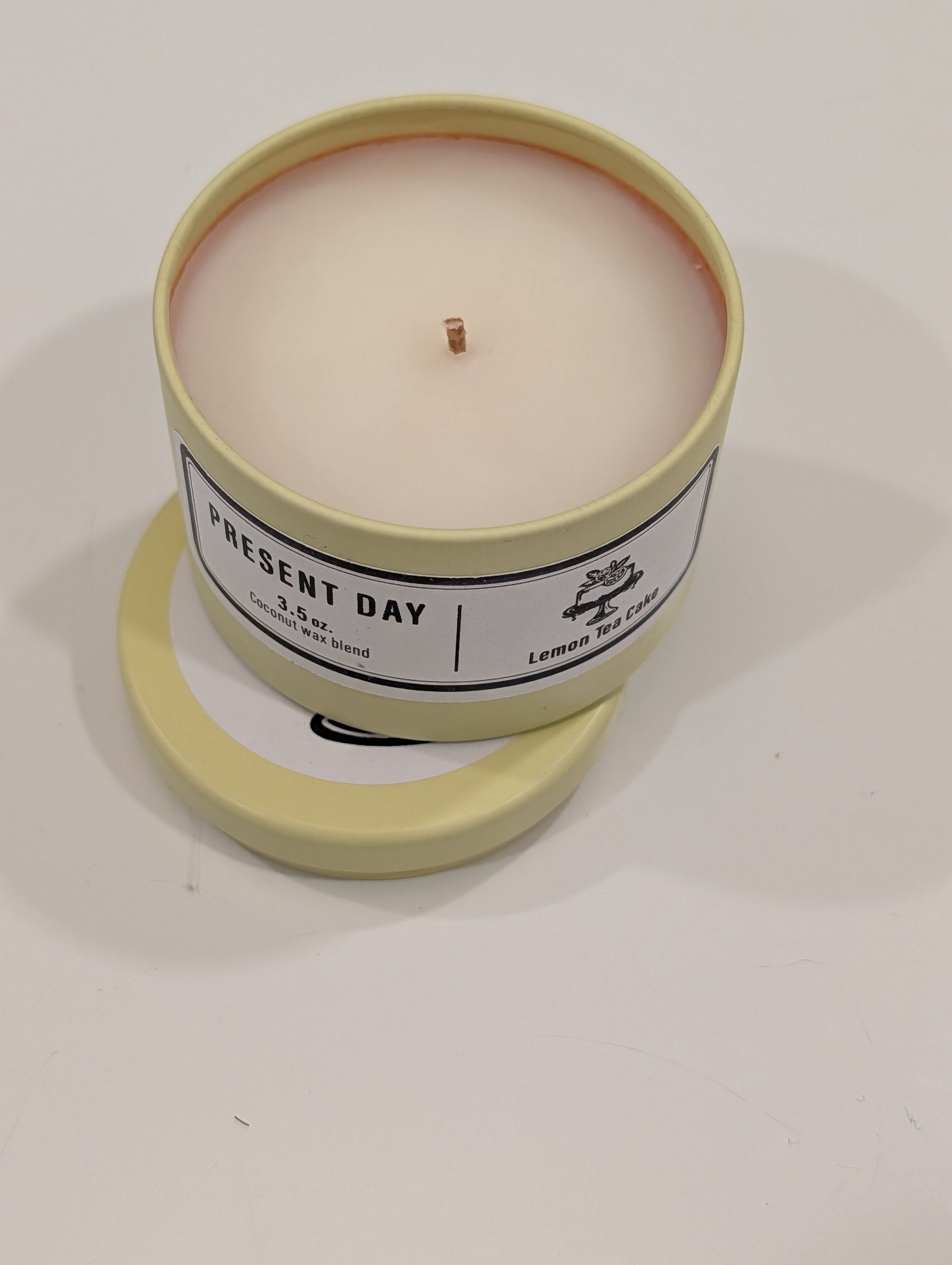 Lemon Tea Cake Candle in a yellow tin with a label on a white counter