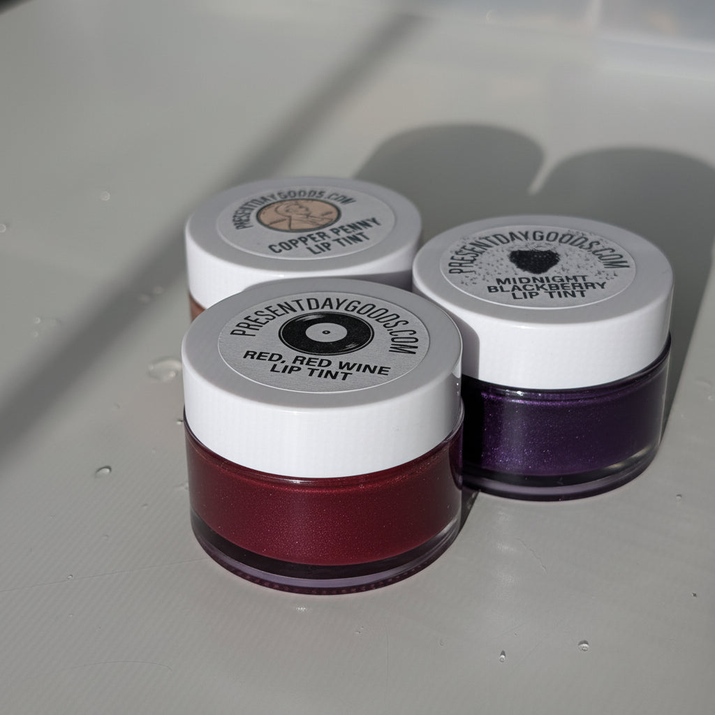 Three small jars with lip tint on a reflective surface