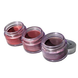 Three small open jars of pink lip balm on a white surface.