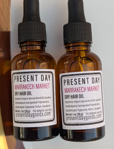 Two amber glass dropper bottles of Present Day Marrakech Market Dry Hair Oil arranged vertically on a white background.