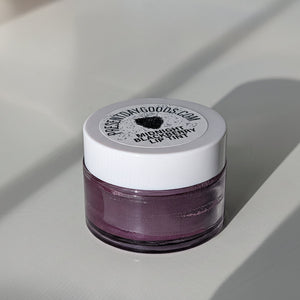 Small jar of lip tint with a white lid on a light gray background