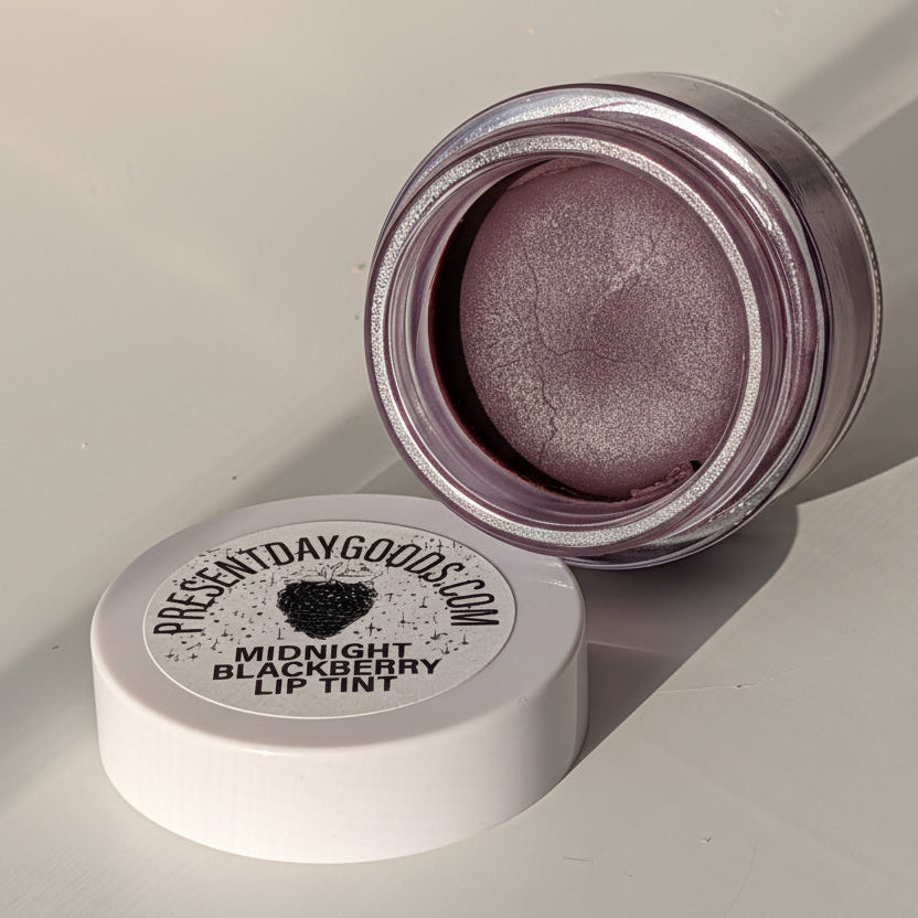 Lip tint container with open lid on a light gray background