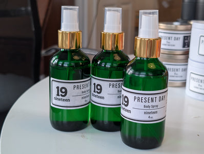 Three green bottles with gold caps labeled 'Present Day' on a white surface.