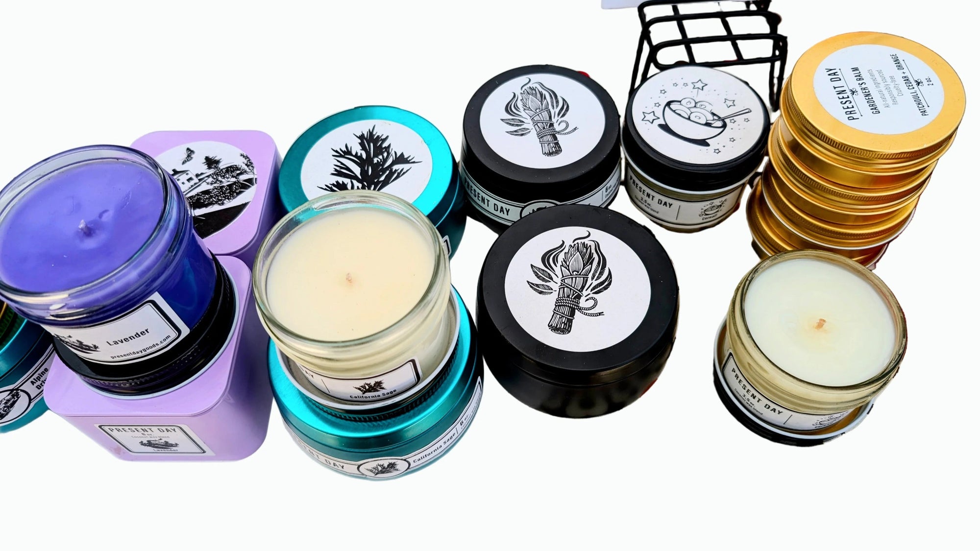 Collection of various candles with different colored containers and labels on a white background.
