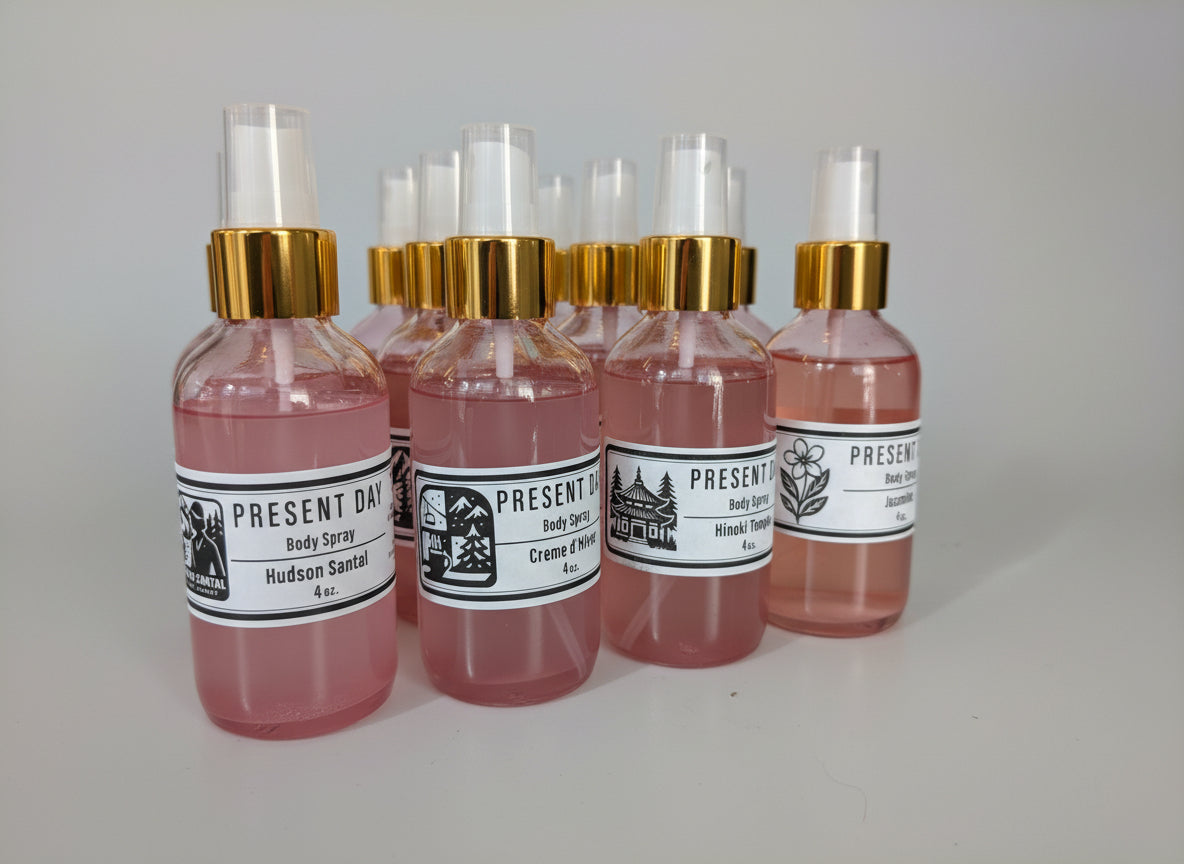 Row of Present Day body spray bottles with pink and clear liquid on a white surface.