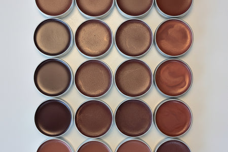 Grid of lip tints in silver tins on a light background