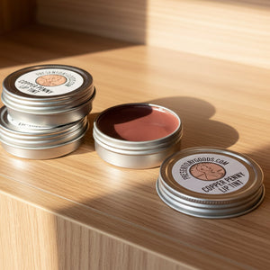 Three tins of copper penny lip tint on a white surface