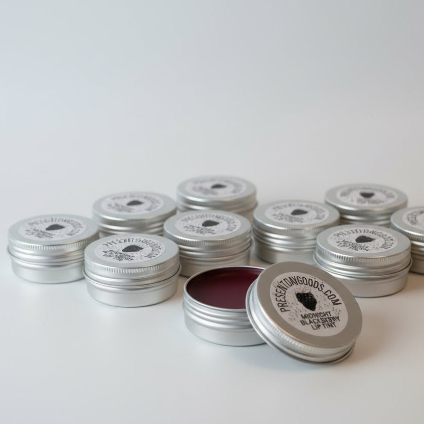 Two tins of lip tint with 'Present Day Goods' labels on a white background