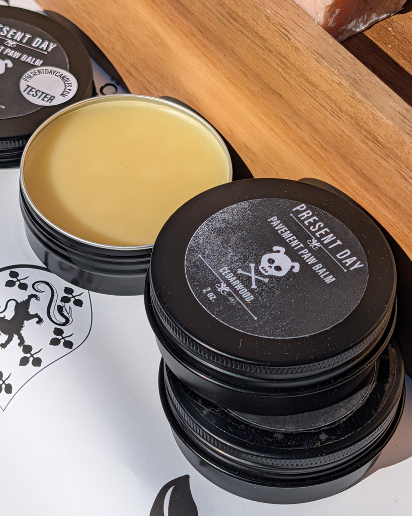 Present Day balm containers with black lids on a white background