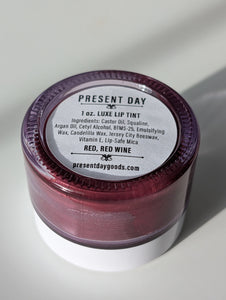 Lip tint container with purple lid and white label on a light gray background