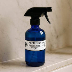 Green spray bottle with black nozzle on a marble surface