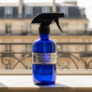 Blue spray bottle with black nozzle on a marble surface