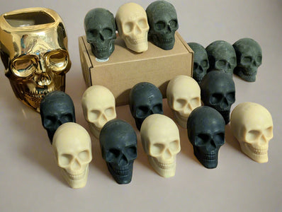 Collection of skull-shaped objects on a wooden surface with a gold skull container.