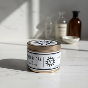 Candle jar with 'Present Day' label on a white surface
