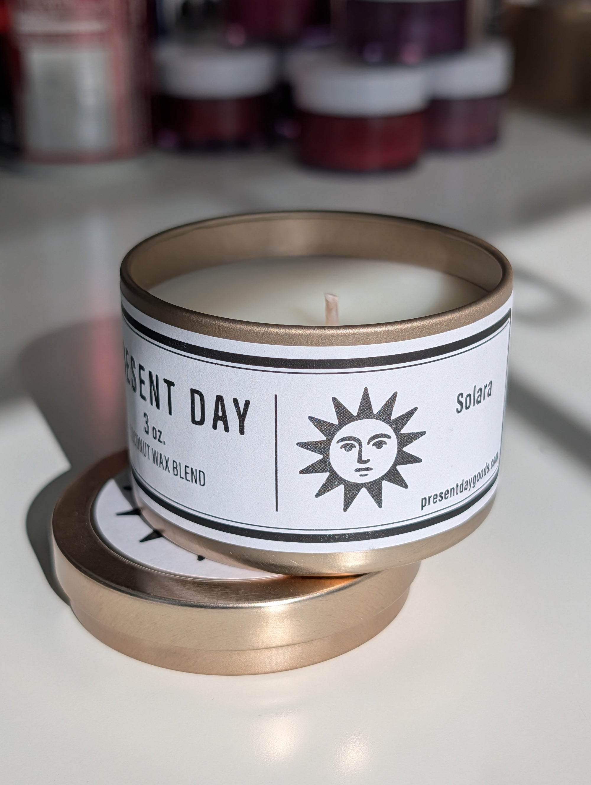 Candle in a metal tin with a label on a white surface