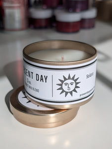 Candle in a metal tin with a label on a white surface