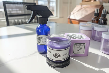 Purple candle and spray bottle on a white surface with a blurred background