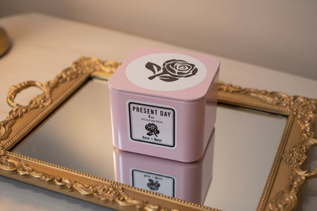 Hand-poured coconut wax candle in a pink square gift tin with a rose design and 'PRESENT DAY' branding.